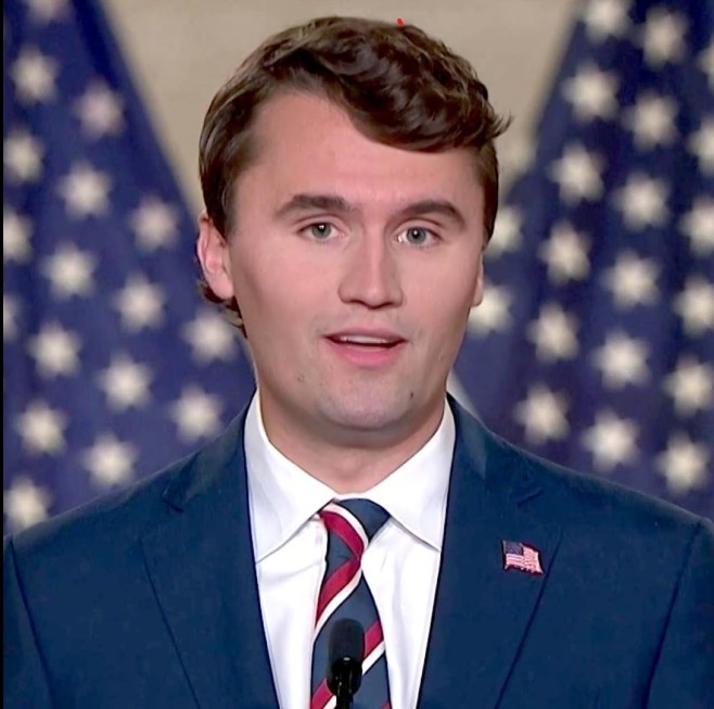 Charlie Kirk portréja, két  USA-csillagos zászlóval a háta mögött.